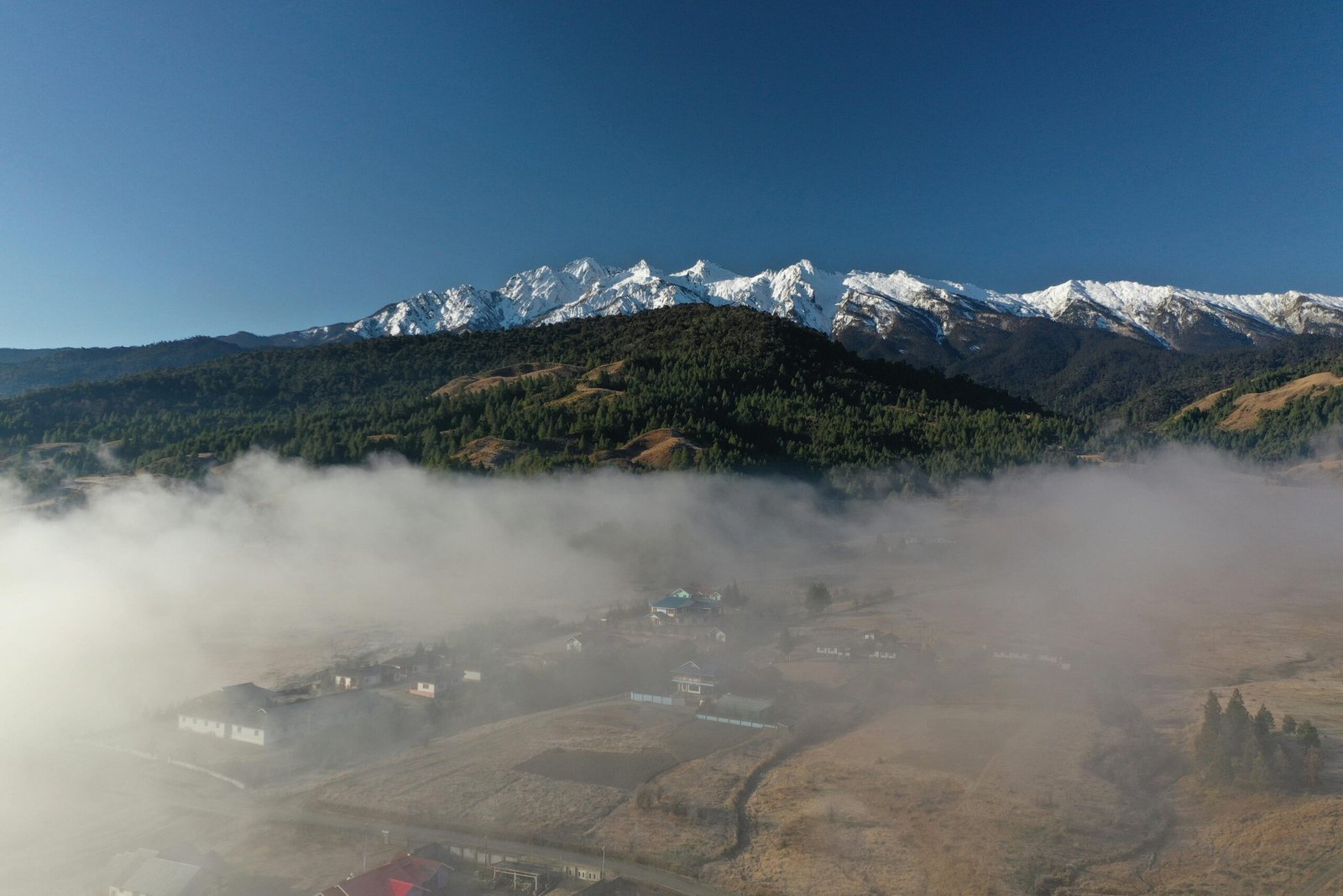 A breathtaking view of a misty valley with snowy mountains in Kargong, perfect for nature and travel enthusiasts.