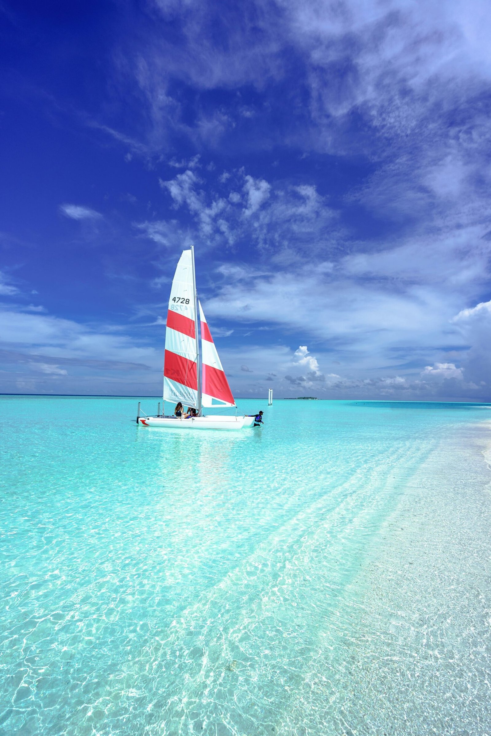 Idyllic scene of a sailboat on pristine turquoise waters under a clear blue sky in the Maldives.