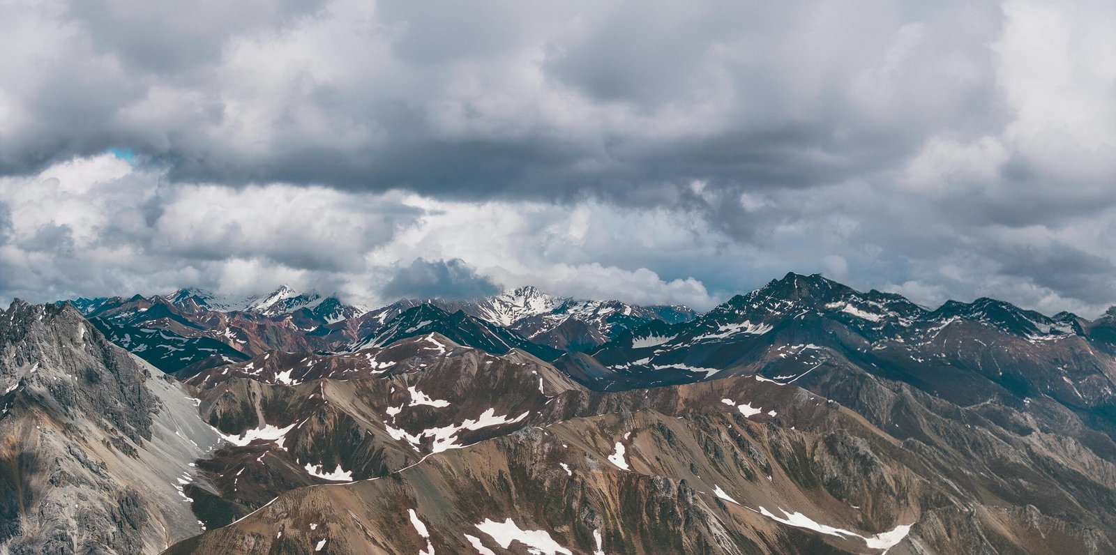 A breathtaking aerial view of the rugged, snow-capped Himalayan peaks under dramatic clouds.